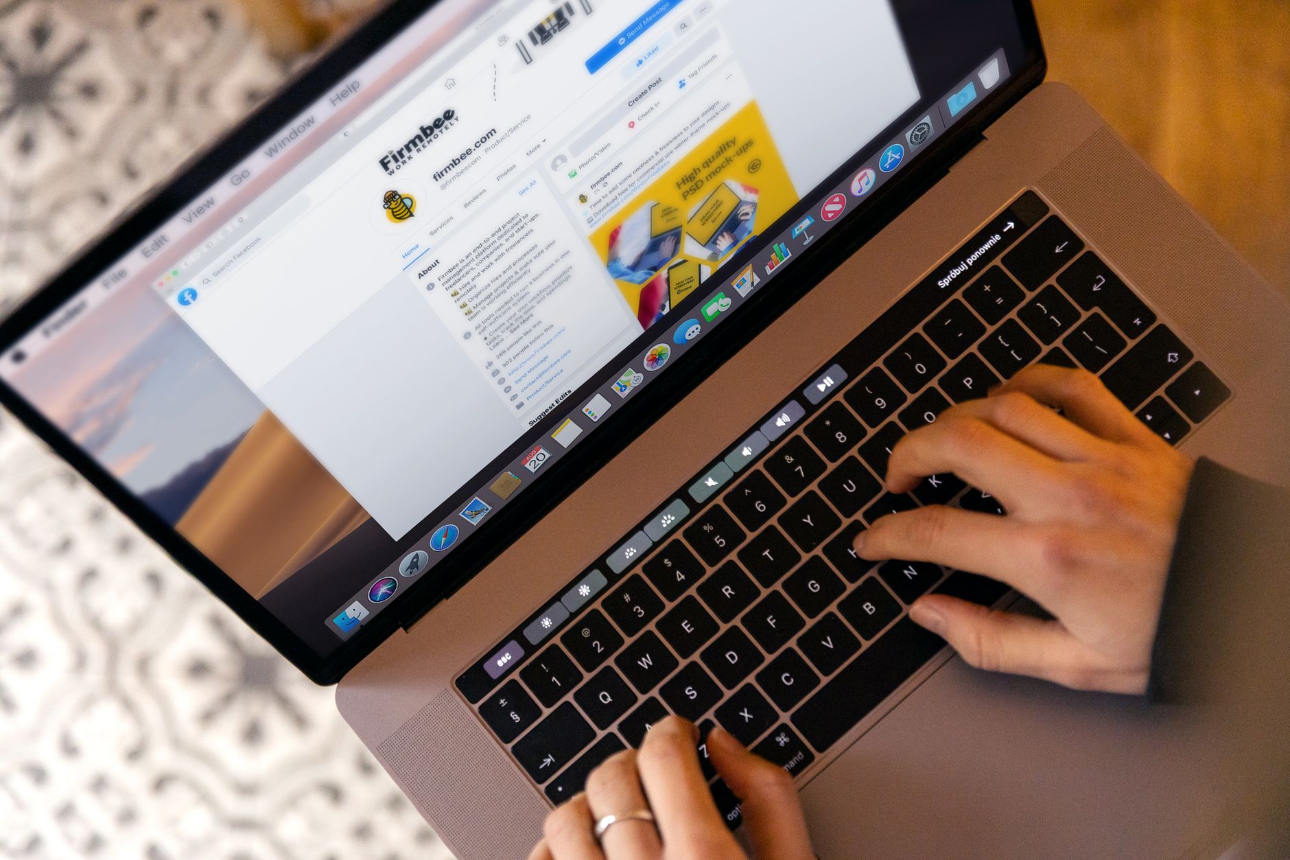 Hands typing on a laptop at a desk while working online