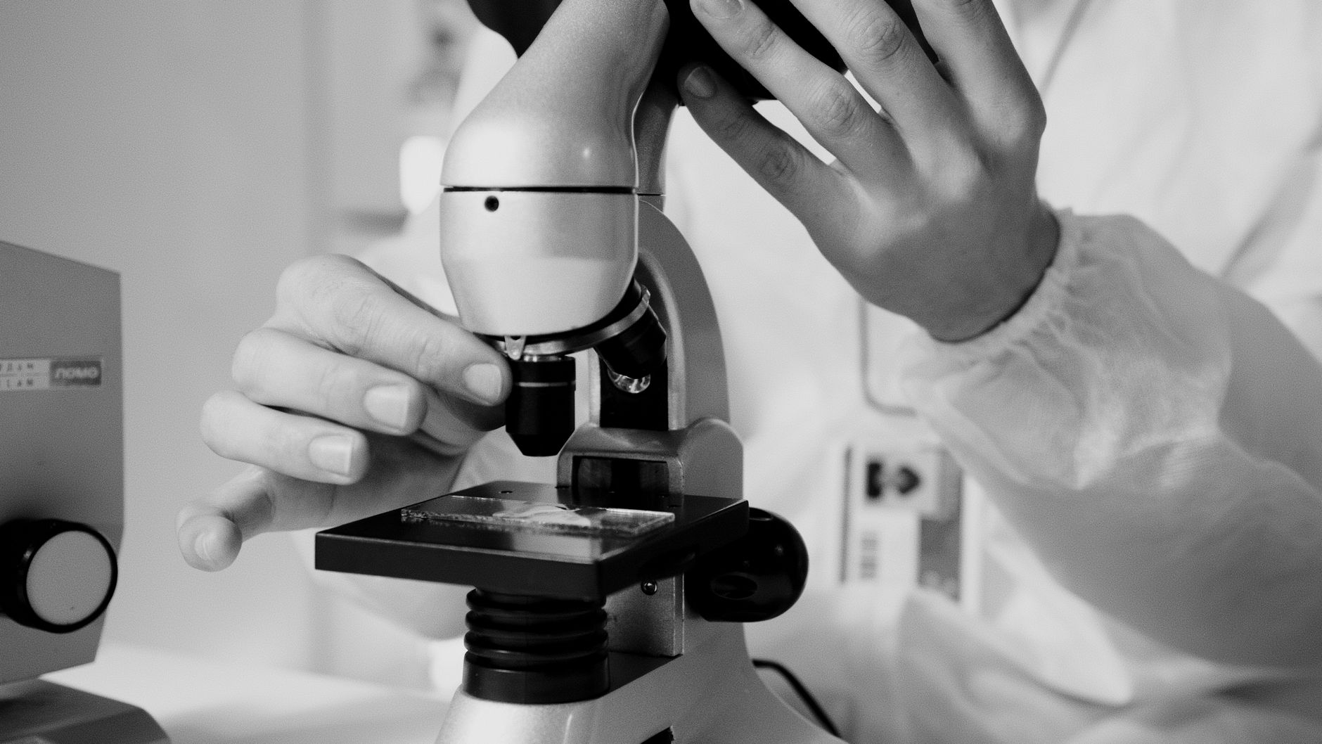 A scientist in a lab coat using a microscope for research in a laboratory setting